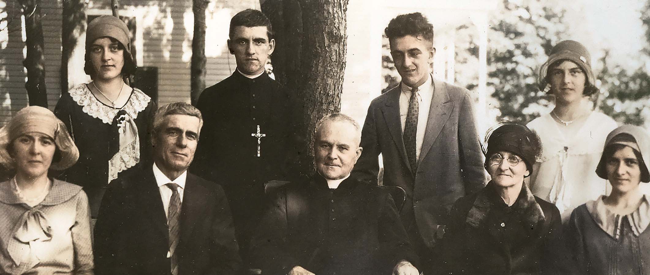 Photographie d'archives : le père Eugène Prévost assis à l'extérieur et entouré des membres de la famille lapointe