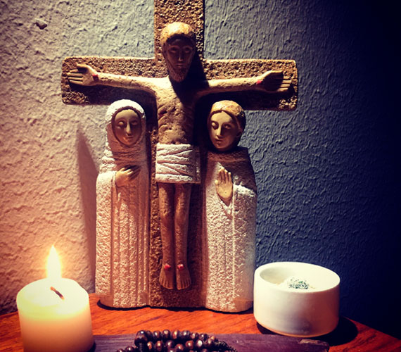 Image d'un crucifix éclairé par des chandelles et à côté duquel se trouvent la Vierge Marie et saint Jean